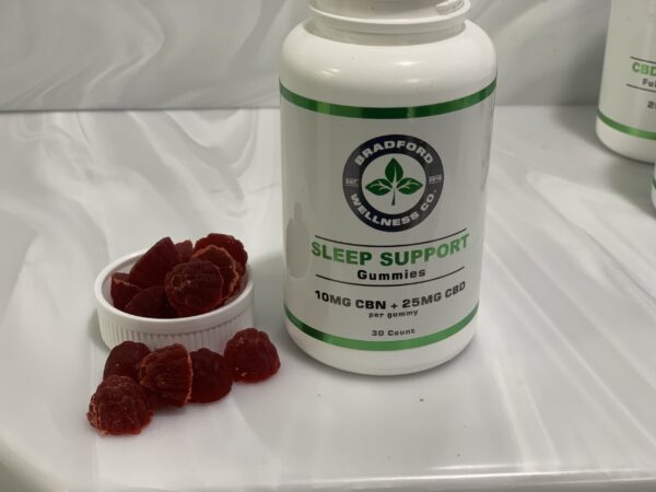 Sleep Support CBD Gummies with the lid off and gummies spread on a white background